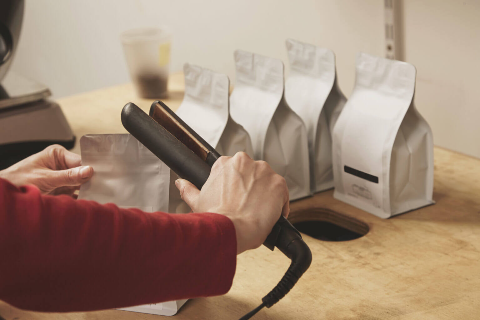 Woman hands getly seal with special device blank bulk packages contain product in small business for retail delivery and sale
Artisan manufacturing process